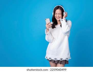 Happy young woman in headphones listening to music on light blue background. Smiling caucasian young woman listening to the podcast e-book music song singer rock band in headphones earphones. - Powered by Shutterstock