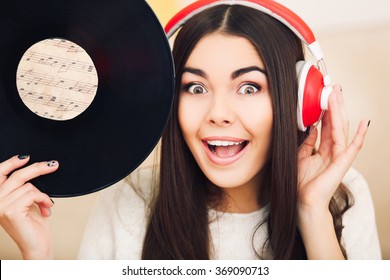 Happy Young Woman With Headphones And Vinyl Record Listening To Music At Home