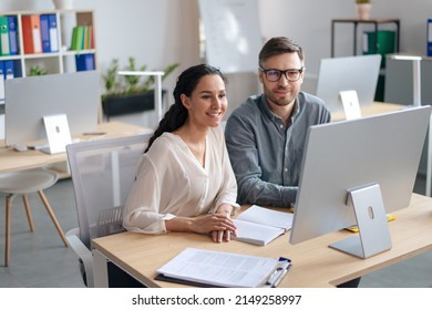 Happy young woman and her male colleague working together, using modern computer in open space office. Cheerful coworkers preparing business project, brainstorming for startup ideas - Powered by Shutterstock