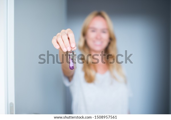 Happy young\
woman hold a keys in her new home. Close up of woman holding key of\
a new house. Close up of real estate agent showing keys of new\
apartment. Woman with new house\
keys.