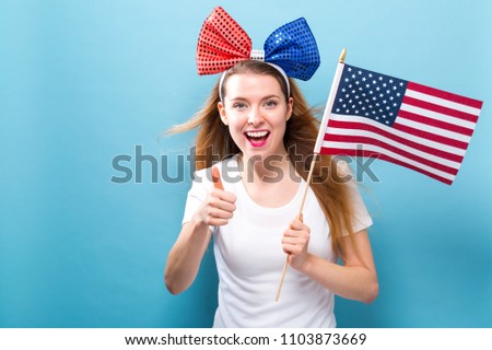 Happy young woman holding an American flag on a blue background