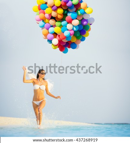 Happy young woman holding balloons, running on beach. Concept of travel, holidays and freedom