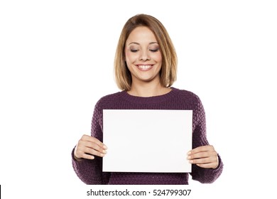 Happy Young Woman Holding A Blank Sheet Of Paper For Advertising