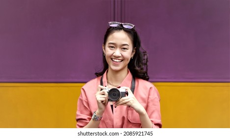 a happy young woman holding a camera   - Shutterstock ID 2085921745