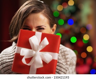 Happy Young Woman Holding Christmas Present Box In Front Of Face