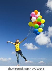 Happy Young Woman Holding Colorful Balloons And Flying Over A Green Meadow