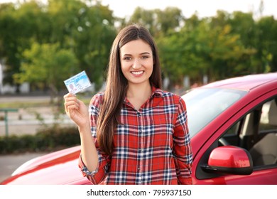 Happy young woman holding driving license near car - Shutterstock ID 795937150