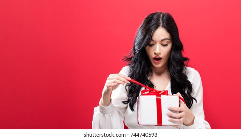 Happy Young Woman Holding A Gift Box On A Solid Background