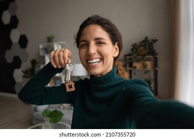 Happy young woman holding keys in hands, recording selfie video, sharing positive experience of apartment purchase, renting first dwelling or moving into renovated house, blogging streaming online. - Powered by Shutterstock