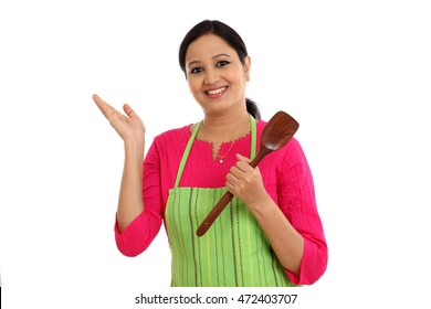 Happy young woman holding kitchen utensil against white background