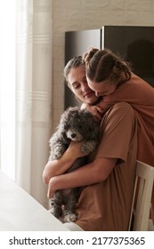 Happy Young Woman Holding Little Dog When Daughter Hugging Her From Behind