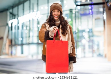 Happy young woman holding shopping bag with blank space for template, logo or design, lady standing near mall with purchase