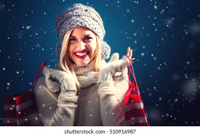 Happy Young Woman Holding Shopping Bags In Snowy Night