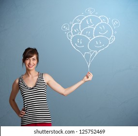 Happy young woman holding smiling balloons drawing