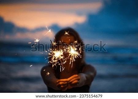Happy young woman holding sparkler celebrating new years eve on the beach. MyRealHoliday