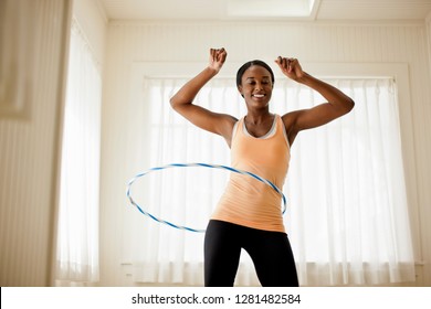 Happy young woman hula hooping in her living room. - Shutterstock ID 1281482584
