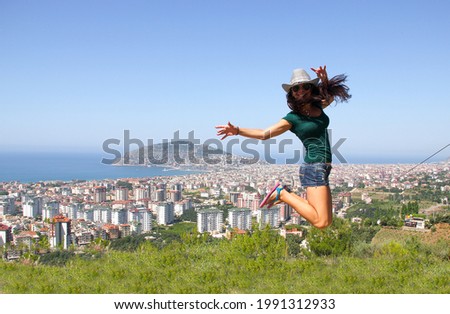Happy young woman is jumping high on the city and sea side. Vacation, adventure idea