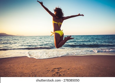 Happy young woman jumping on the beach. Summer vacation and freedom concept