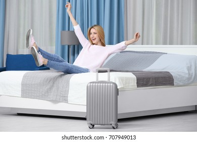 Happy Young Woman Jumping On Bed In Hotel Room