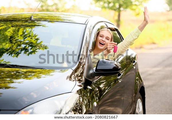 Happy young woman\
with key sitting in new\
car