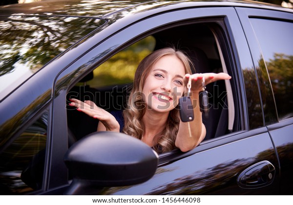 Happy young woman with\
keys in auto.
