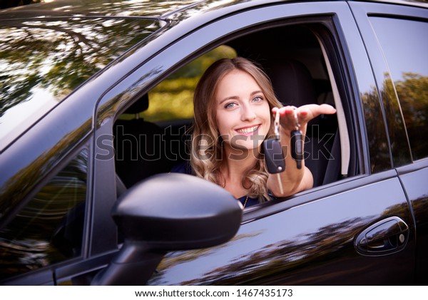Happy young woman with\
keys in auto.