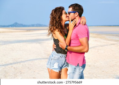 Happy young woman kissing her handsome boyfriend , enjoy their summer vacation on amazing beach, lifestyle portray of stylish hipster couple in love.