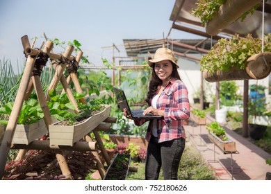 Happy Young Woman With Laptop In The Farm. Modern Urban Farming Concept