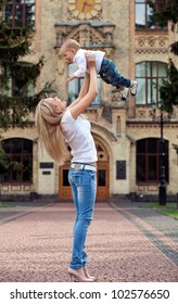 Happy Young Woman Lifting Her Son High Up Outdoors