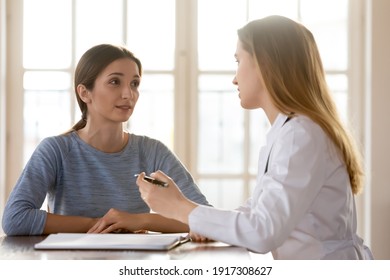 Happy Young Woman Listening To Female General Practitioner At Checkup Meeting In Clinic Office. Professional Surgeon Gynecologist Therapist Doctor Giving Healthcare Medical Consultation To Patient.