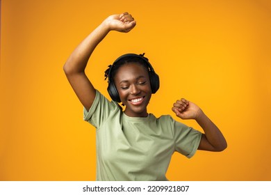 Happy young woman listening to music in headphones against yellow background - Powered by Shutterstock