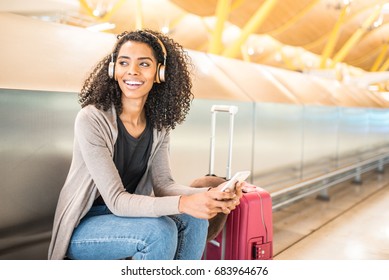 happy young woman listening music with headphones and mobile phone at the airport