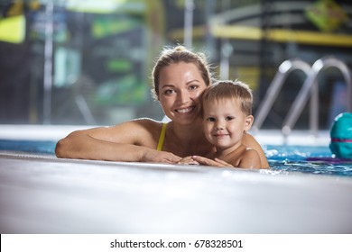 Happy Young Woman With Little Son Smiling At Edge Of Indoor Swimming Pool