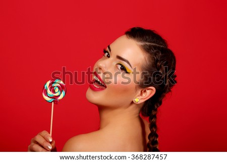 happy young woman with lollipop, against a background of red background