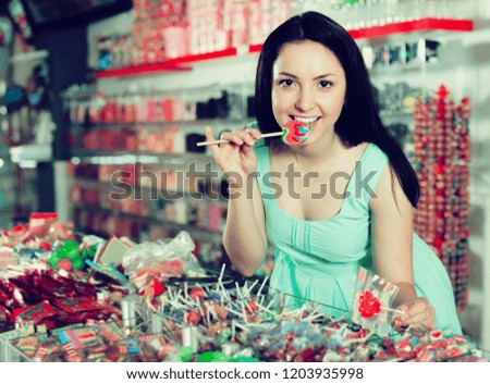 Happy young woman with lollipop at candy shop