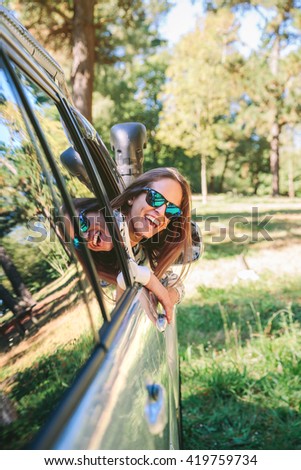 Happy young woman looking back through the window car