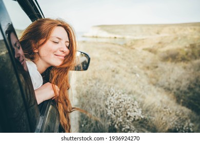 Happy young woman looking out of car window. 