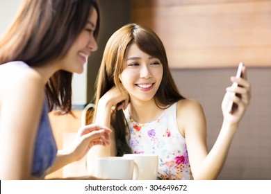happy young woman looking at phone in coffee shop