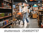 Happy young woman looking at product at grocery store. Smiling woman shopping in supermarket.