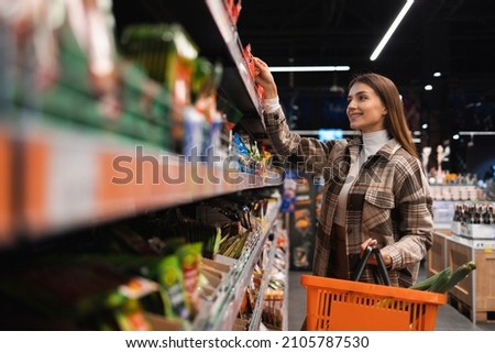 Happy young woman looking at product at grocery shop. Customer buying food at the supermarket