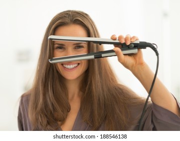 Happy Young Woman Looking Through Hair Straightener