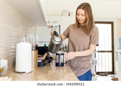 Happy young woman making coffee in kitchen - french press coffee. Caucasian female model in her twenties at home kitchen. Lifestyle concept - Powered by Shutterstock