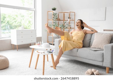 Happy young woman making pedicure in living room