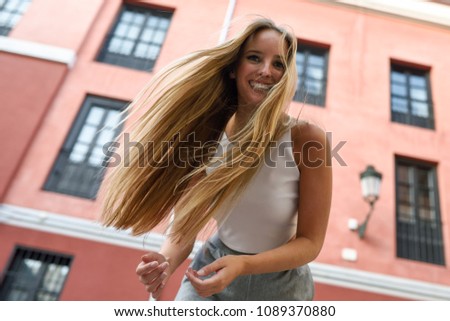 Happy young woman with moving hair in urban background