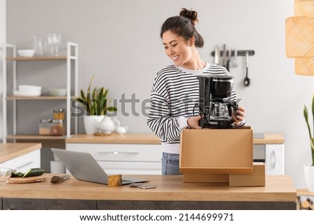 Happy young woman with new coffee maker at home. Online shopping