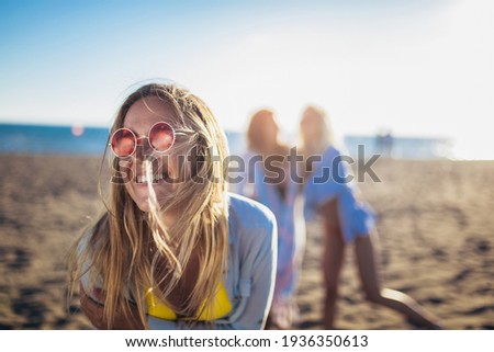 Happy young woman on the beach with her friends in background. Group of friends enjoying on beach holiday.