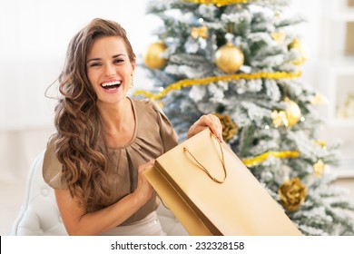 Happy Young Woman Opening Shopping Bag Near Christmas Tree