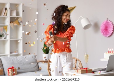 Happy Young Woman With Party Popper Celebrating Birthday At Home