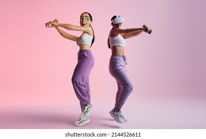 Happy young woman partying as a 3D avatar in the metaverse. Cheerful young woman having fun while wearing virtual reality goggles. Young woman enjoying a 3D simulation in a studio. - Shutterstock ID 2144526611
