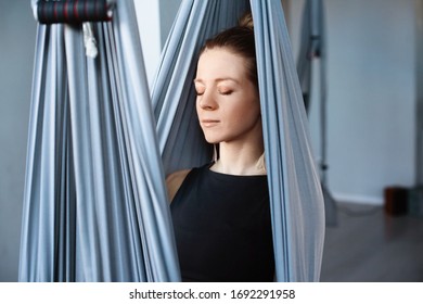 A happy young woman performs yoga exercises with a hammock. Yoga-meditation in a hammock. Concept of a healthy lifestyle and relaxation. A girl is resting in a yoga hammock - Powered by Shutterstock